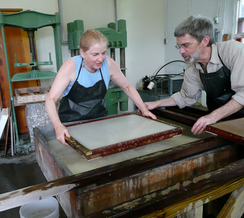 Tim Barrett assists a student in the art of papermaking.