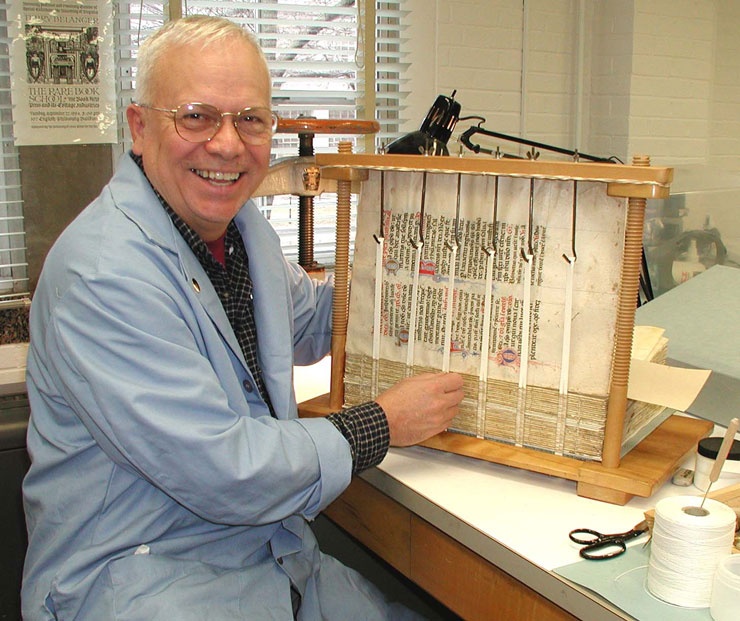 Gary Frost smiles and props up a book he is binding