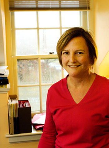 Karen Copp stands in front of a window and smiles at the camera