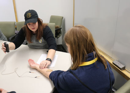 Neuroscience PhD student Emma Thornburg demonstrates how the TENS unit works during the Kids Go STEM event.