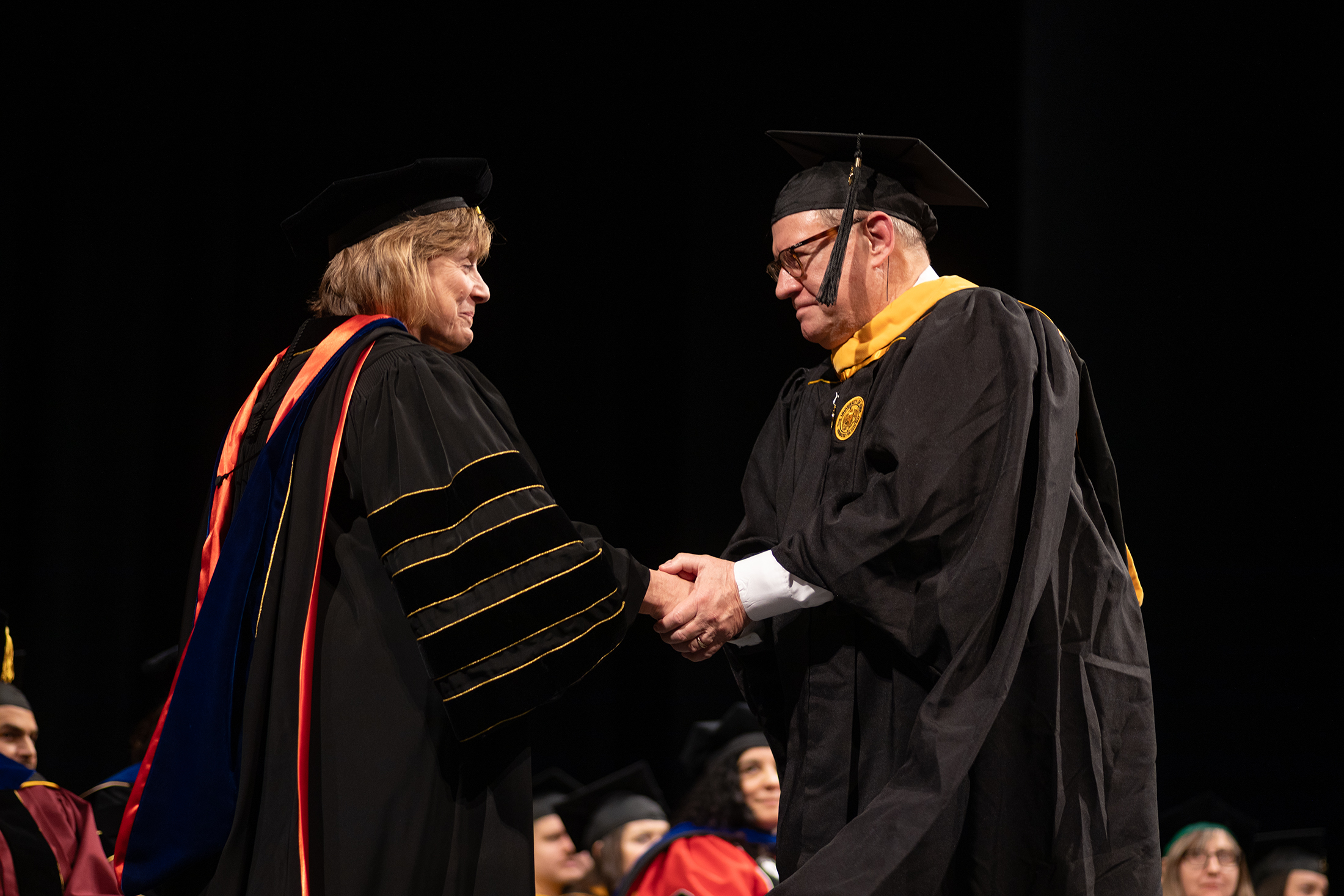 Jim Brewer shakes the hand of University of Iowa President Barbara Wilson.