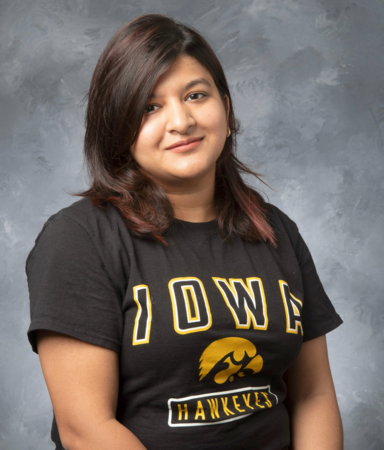 Rivu poses for a headshot wearing a grey t-shirt with the IOWA in gold across the chest a gold tigerhawk.