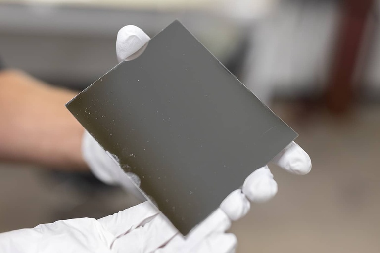 Jacob Payne holds a multi-coated mirror for an X-ray telescope