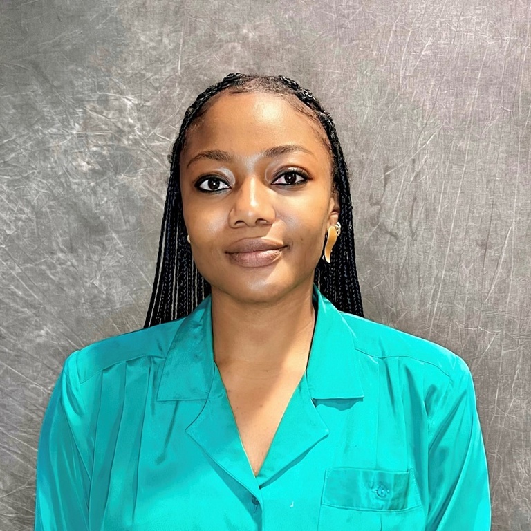 Headshot photo of Simi Olatunbosun. She is wearing a teal collared shirt and is standing against a gray background.