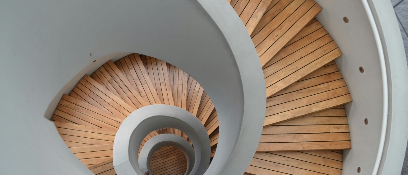 Spiral staircase with wooden stairs and white railings seen from above