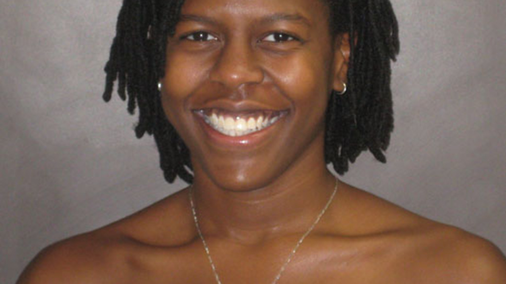Carmen Smith smiles into the camera in front of a gray background